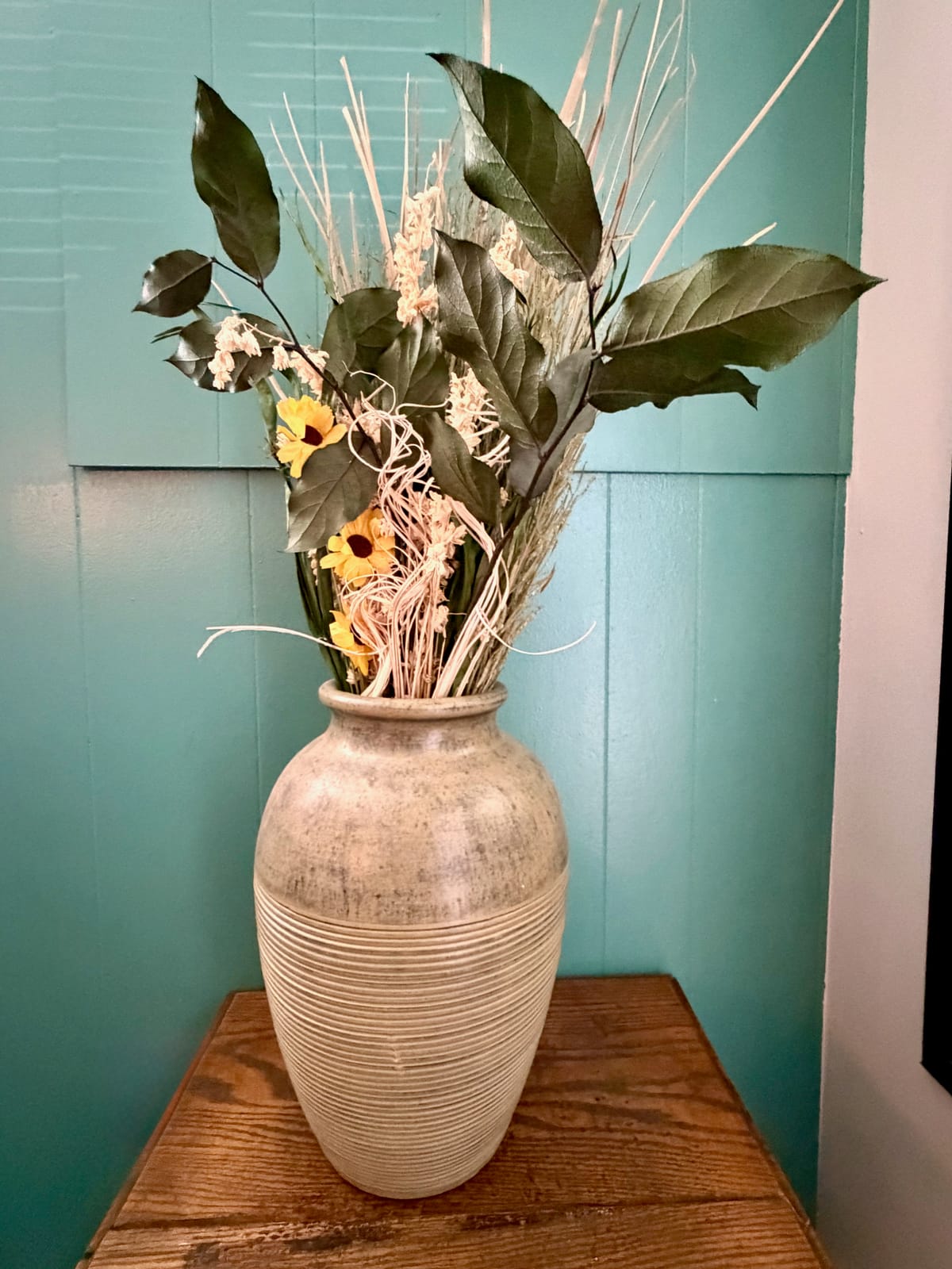 The Garden Room — large ceramic vase with lush dried florals, sunflowers, leaves, and pampas grass against teal panel wall
