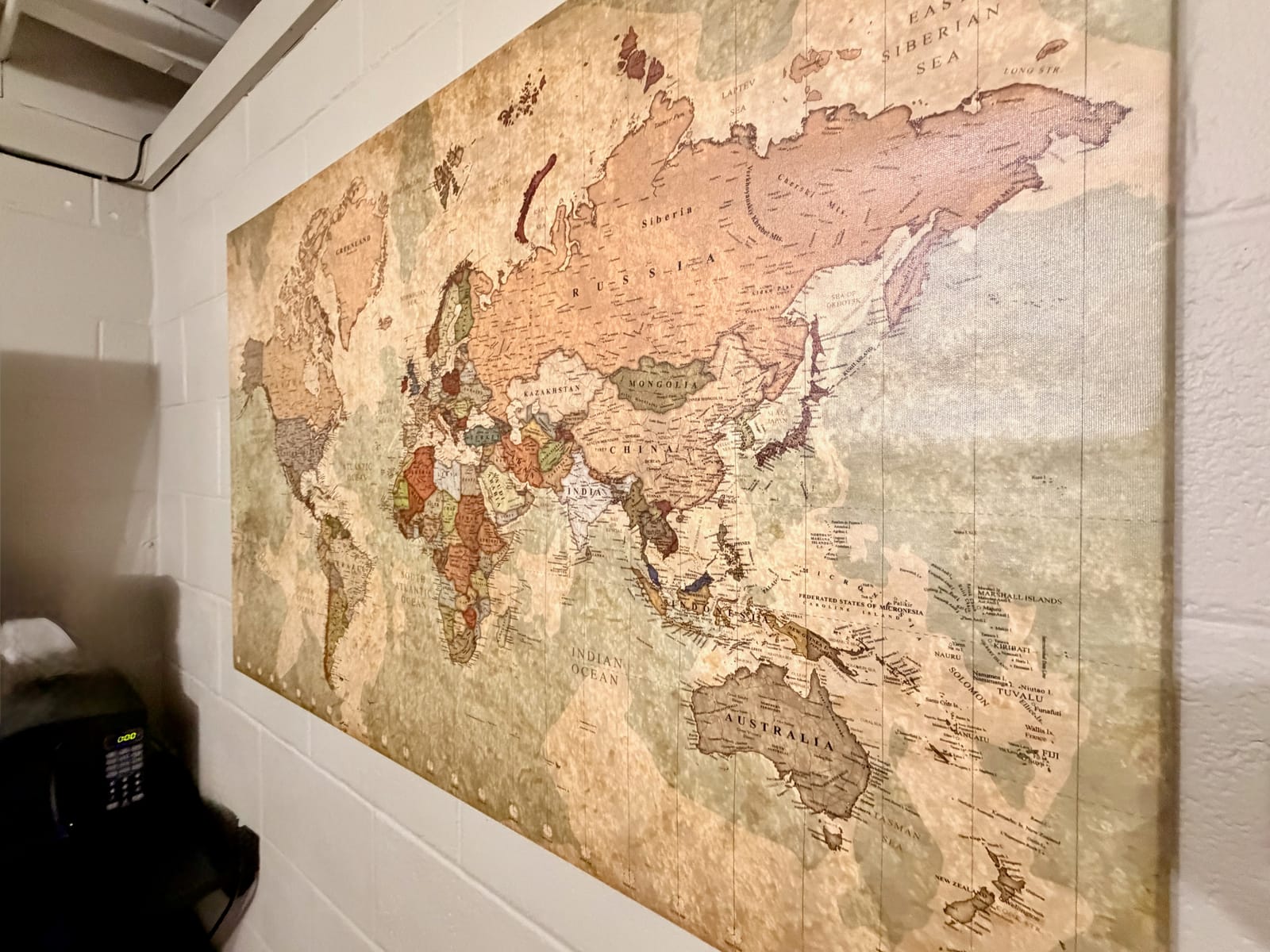 The Traveler's Den — oversized vintage world map canvas mounted on white brick wall
